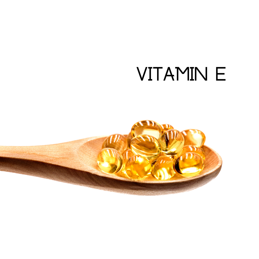Wooden spoon with vitamin E capsules on a white background