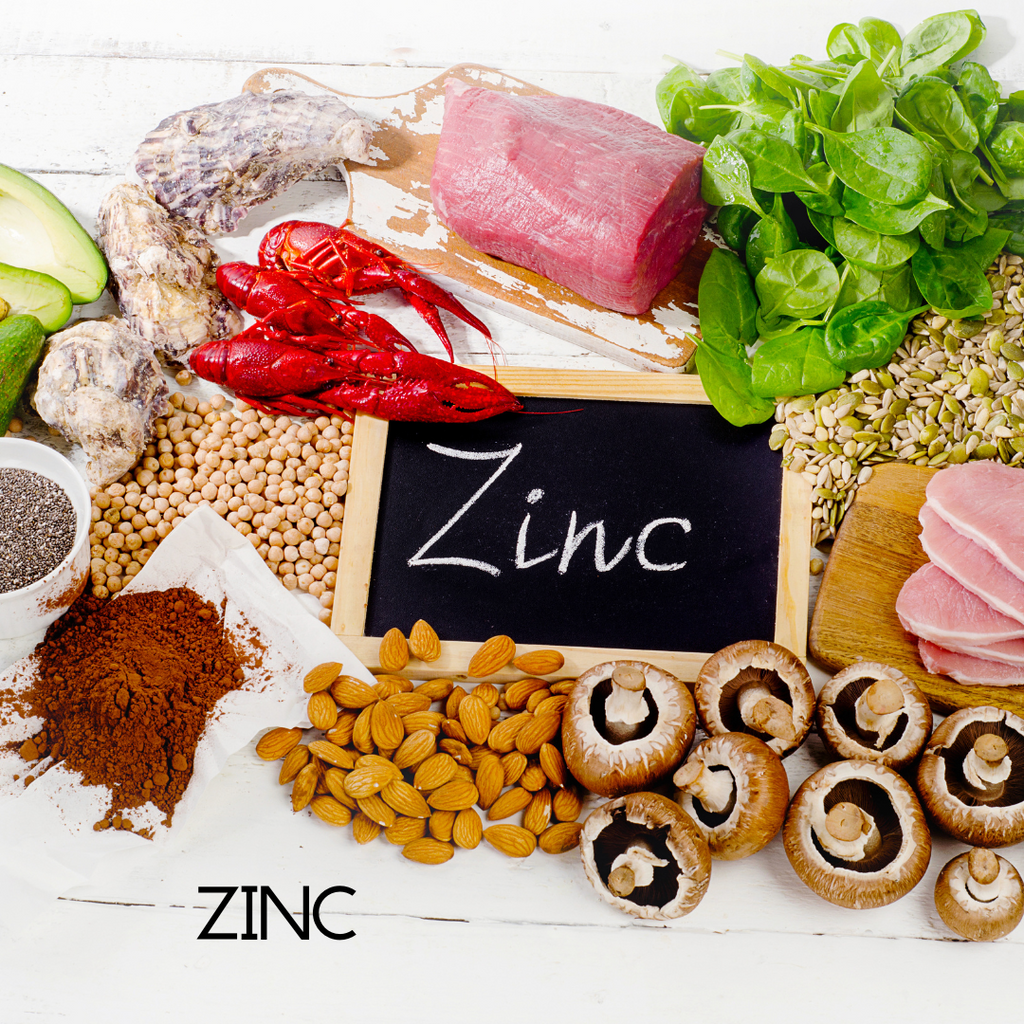 Assorted foods rich in zinc with a blackboard displaying 'Zinc' on a white background.